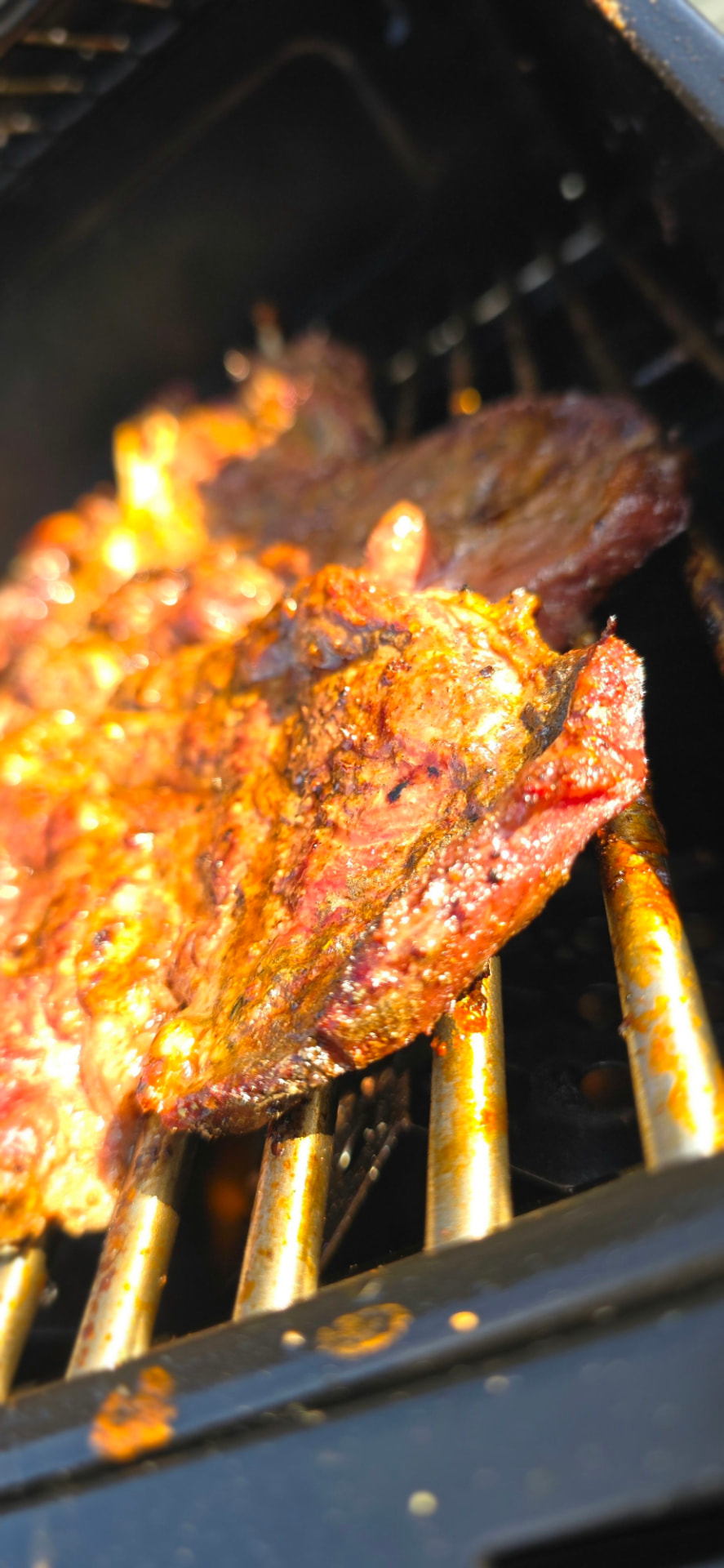 Chuck steak sizzling over hot coals with a caramelised crust