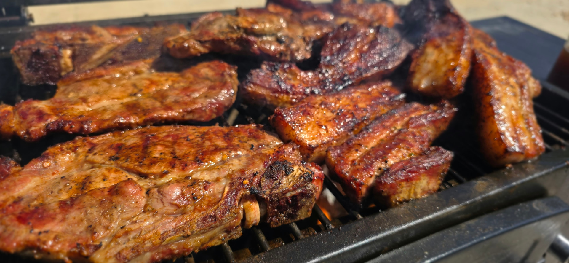 Pork belly sizzling over open coals with crisp, rendered edges